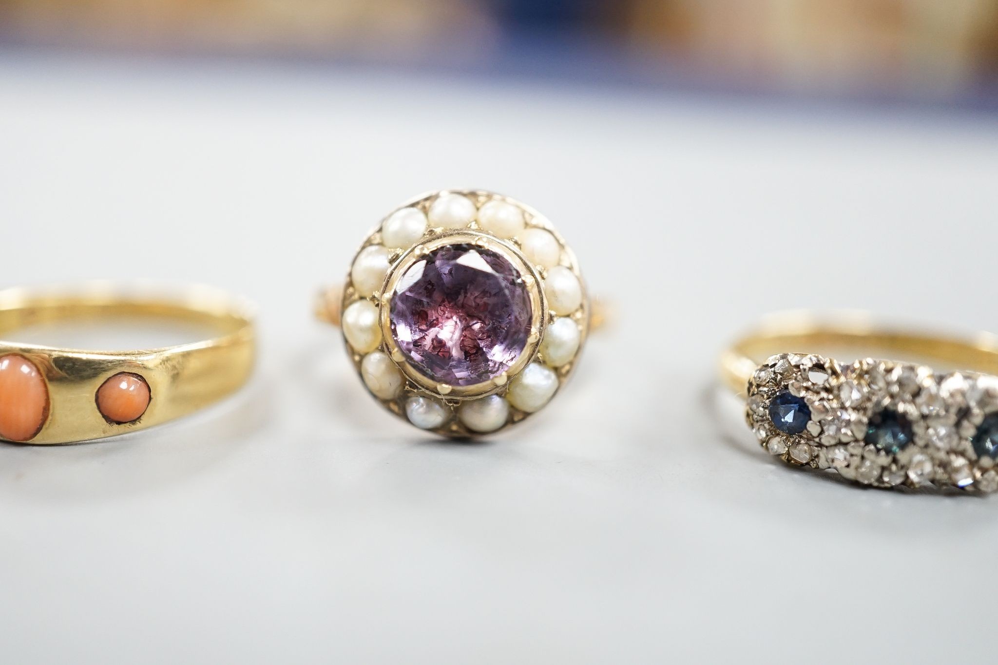 An early 20th century 18ct gold and gypsy set three stone coral ring, size P/Q, a similar sapphire and diamond set triple cluster ring, 5.5 grams, two similar 9ct gold rings, 7.7 grams and a yellow meta, foil backed amet